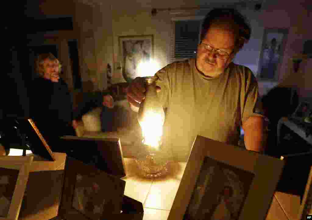 Jeff Willard lights a candle in his living room as his girlfriend, Diana Conte, back left, and her son, Ricky, wait for electricity to return in Ventnor City, N.J., Oct. 30, 2012. 