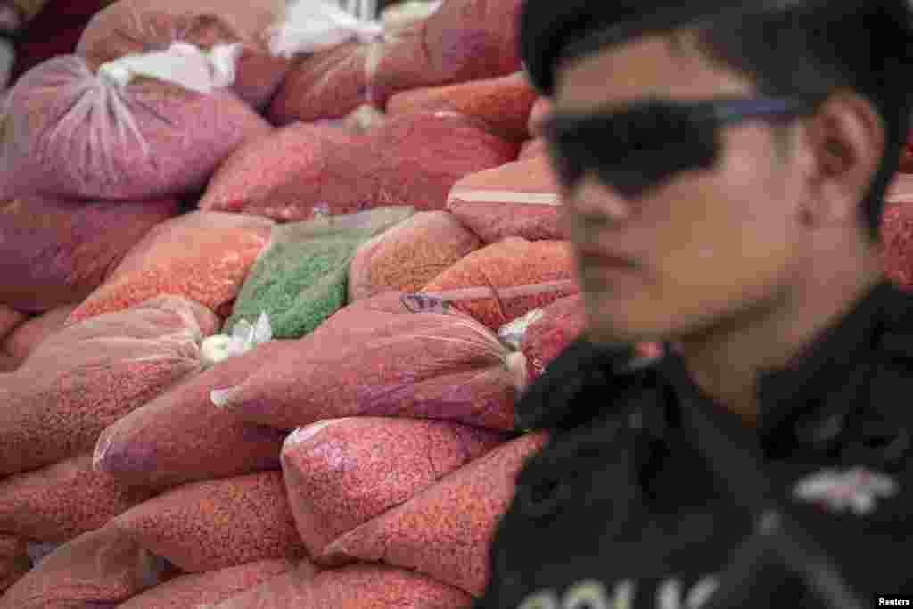 A police officer guards bags of methamphetamine pills during a destruction ceremony in Ayutthaya province, north of Bangkok, Thailand. About 7,340 kg (16,182 lbs) of confiscated drugs, among them methamphetamine, marijuana, heroin and opium worth more than 22 billion baht ($651,000,000), were destroyed.