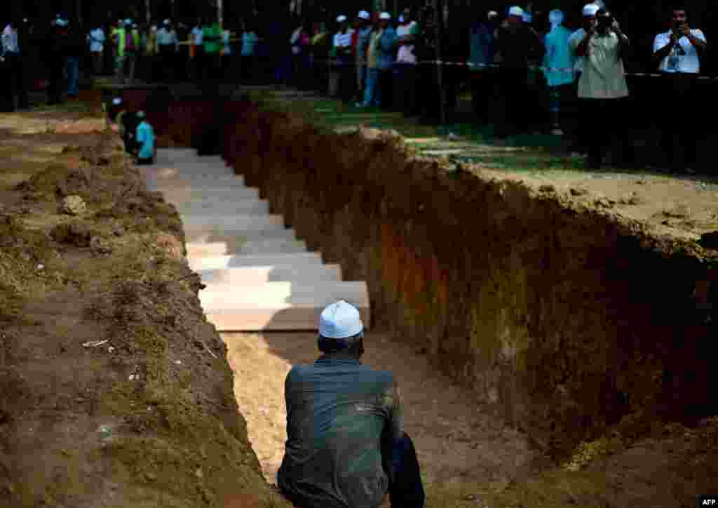 A Malaysian Muslim man sits near a pit during the re-burial of remains believed to be those of ethnic Rohingya found at human-trafficking camps at Kampung Tualang, some 16kms east of Alor Setar. Authorities held a sombre mass funeral for 21 suspected ethnic Rohingya found in human-trafficking graves last month.