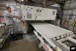 A worker begins production of a kitchen countertop that is being cut from imported quartz slabs from China in the production facility at Marble Uniques in Tipton, Ind., May 3, 2019.