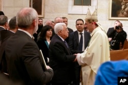 Palestinian President Mahmoud Abbas congratulates Archbishop Pierbattista Pizzaballa, apostolic administrator of the Latin Patriarch of Jerusalem, during the Christmas Midnight Mass in Saint Catherine's Church at the Church of the Nativity, in Bethlehem, Dec. 25, 2016.