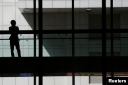 FILE- A woman talks on phone inside the Bank of China head office building in Beijing, China.