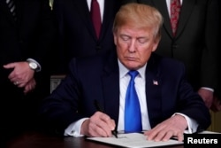 FILE - U.S. President Donald Trump signs a memorandum on intellectual property tariffs on high-tech goods from China, at the White House in Washington, DC, U.S., March 22, 2018.