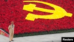 A police stands guard next to a decoration with the communist logo at the National Convention Center, the venue for the 11th Party Congress, in Hanoi January 12, 2011