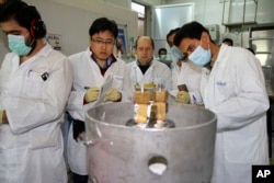 FILE - Unidentified International Atomic Energy Agency inspectors and Iranian technicians cut the connections between the twin cascades for 20 percent uranium enrichment at Natanz facility, 322 kilometers from Tehran, Iran, Jan. 20, 2014.