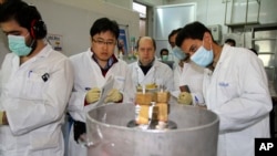 FILE - Unidentified International Atomic Energy Agency inspectors and Iranian technicians cut the connections between the twin cascades for 20 percent uranium enrichment at Natanz facility, 322 kilometers from Tehran, Iran, Jan. 20, 2014. 