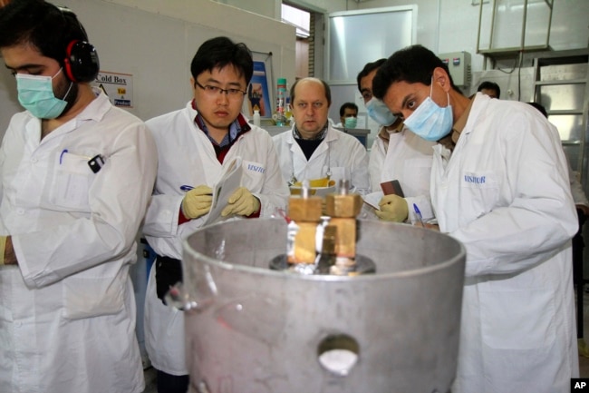 FILE - Unidentified International Atomic Energy Agency inspectors and Iranian technicians cut the connections between the twin cascades for 20 percent uranium enrichment at Natanz facility, 322 kilometers from Tehran, Iran, Jan. 20, 2014.