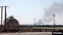 Smoke rises near oil tanks after heavy fighting between rival militias broke out near the airport in Tripoli, July 23, 2014. 