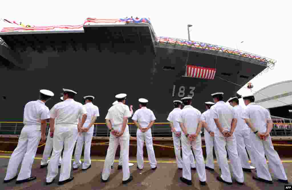 Crew members of Japan's newest warship stand along the vessel during a launch ceremony in Yokohama, August 6, 2013.