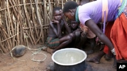 In this photo taken Tuesday, Oct. 17, 2017, a Karamojong woman prepares a meal at her village in the semi-arid savannah region of Karamoja, in northeastern Uganda. (AP Photo/Adelle Kalakouti)