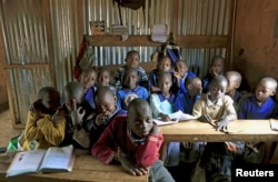 FILE - A class of children between the ages of 6 and 7 years old pose for pictures in their classroom at Gifted Hands Educational Center in Kenya's Kibera neighborhood in the capital Nairobi, September 2015.