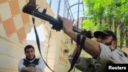 A Free Syrian Army fighter inspects his weapon in the Khan al-Assal area near Aleppo, April 27, 2013. 