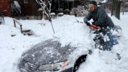 Một cư dân dọn tuyết khỏi xe ô tô ở St. Louis, Missouri, hôm 12/1.