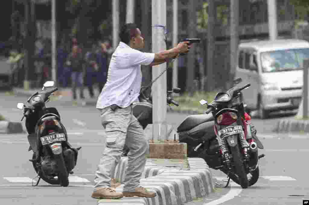 A plainclothes police officer aims his gun at attackers during a gun battle following explosions in Jakarta.