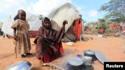 FILE - Kadija Mohamed cooks food for her children in a camp set up for internally displaced people in Dinsoor in southern Somalia, Jan. 5, 2012. 