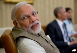 Indian Prime Minister India Narendra Modi looks over his shoulder to speak with an aide during his meeting with President Barack Obama in the Oval Office of the White House in Washington, June 7, 2016.