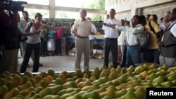 Ansyen prezidan ameriken George W. Bush (nan mitan) te vizite R. Perry Import-Export, yon konpayi kap voye mango ayisyen al vann aletranje. Foto achiv: 10 out 2010.