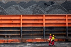 Pekerja berjalan di dekat kapal tunda yang membawa tongkang batu bara di pelabuhan di Palembang, Sumatera Selatan, 4 Januari 2022. (Foto: Antara/Nova Wahyudi via REUTERS)