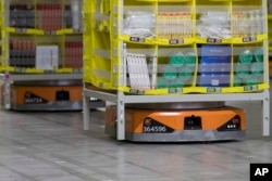 FILE - Pods full of merchandise are moved around the floor by robotic drives, named Amazon robots, at the Amazon fulfillment center in the Staten Island borough of New York, Dec. 5, 2018.