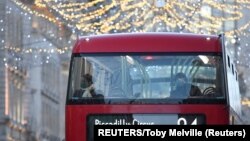 新一轮冠状病毒病(新冠肺炎)在蔓延中，英国伦敦的公交乘客在新限制措施出台前向外张望圣诞彩灯。（当地时间2020年12月15日）