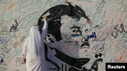 Un hombre escribe sobre un mural dedicado al emir Sheikh Tamim bin Hamad Al Thani en Doha, Catar.