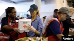 FILE - First lady Melania Trump helps a volunteer hand out meals during a visit with flood survivors of Hurricane Harvey at a relief center in Houston, Texas, Sept. 2, 2017.