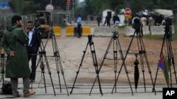 FILE - Pakistani journalists are seen at a stake-out in Islamabad, Pakistan, Nov. 6, 2013. Recently, a Pakistani government body, established to regulate private TV channels, has started asserting itself in ways that have raised concerns with media watchdogs.