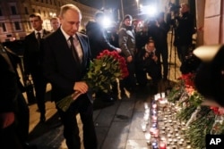 Russian President Vladimir Putin, left, lays flowers at a place near the subway station in St.Petersburg, Russia, Monday, April 3, 2017. A bomb blast tore through a subway train deep under Russia's second-largest city, killing more than 10 people.