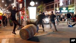 FILE - Protesters overturn trash cans as police try to clear a violent crowd, Sept. 16, 2017, in University City, Mo., a St. Louis suburb.