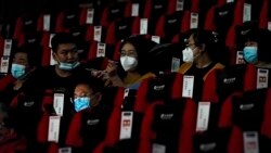 People wearing face masks to help curb the spread of the coronavirus chat each other as the watch a film at Poly Cinema in Beijing on Thursday, Feb. 25, 2021. With coronavirus well under control in China and cinemas running at half capacity, moviegoers are smashing China's box of