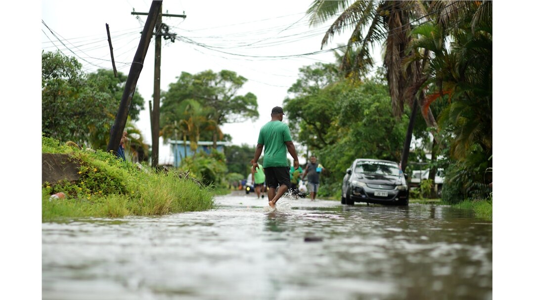 Warga berjalan melewati jalanan yang tergenang banjir di Suva, 14 Desember 2020. (Foto: Leon LORD / AFP)