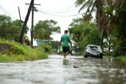 Warga berjalan melewati jalanan yang tergenang banjir di Suva, 14 Desember 2020. (Foto: Leon LORD / AFP)