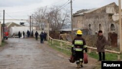 A firefighter carrying fire hoses walks near the scene of a fire that broke out in a drug abuse treatment center in Baku, Azerbaijan, March 2, 2018.