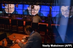 RUSSIA -- A man drinks a coffee in front of screens broadcasting Russian President Vladimir Putin's annual press conference, at a bar in Moscow, December 20, 2018.