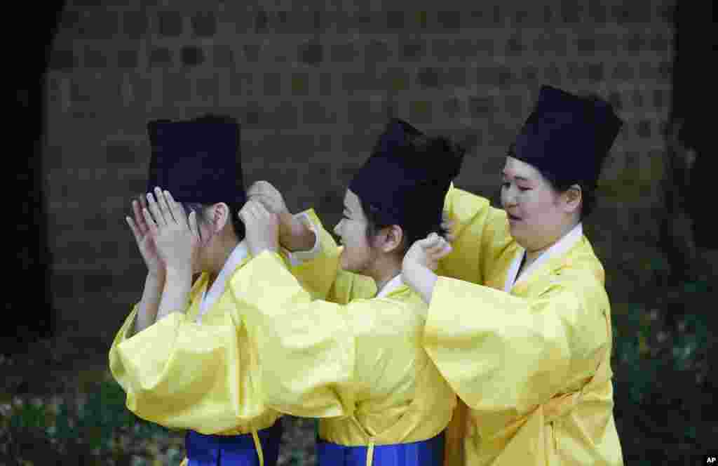 Performers help each other to prepare for the re-enactment ceremony of royal carriage parade for Sajik Daeje in Seoul, South Korea.
