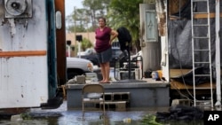 Elida Dimas looks at floodwaters from her porch, in the aftermath of Hurricane Irma, in Immokalee, Florida, Sept. 11, 2017.