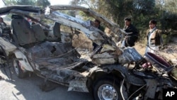 People look at the remains of a passenger minibus near Hungu in Pakistan's northwest province, Monday, Jan. 17, 2011.