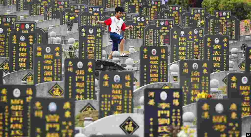 A Chinese boy runs along gravestones during the Qingming Festival or Tomb Sweeping Day outside Kuala Lumpur, Malaysia. Chinese people honor the dead during the annual festival.