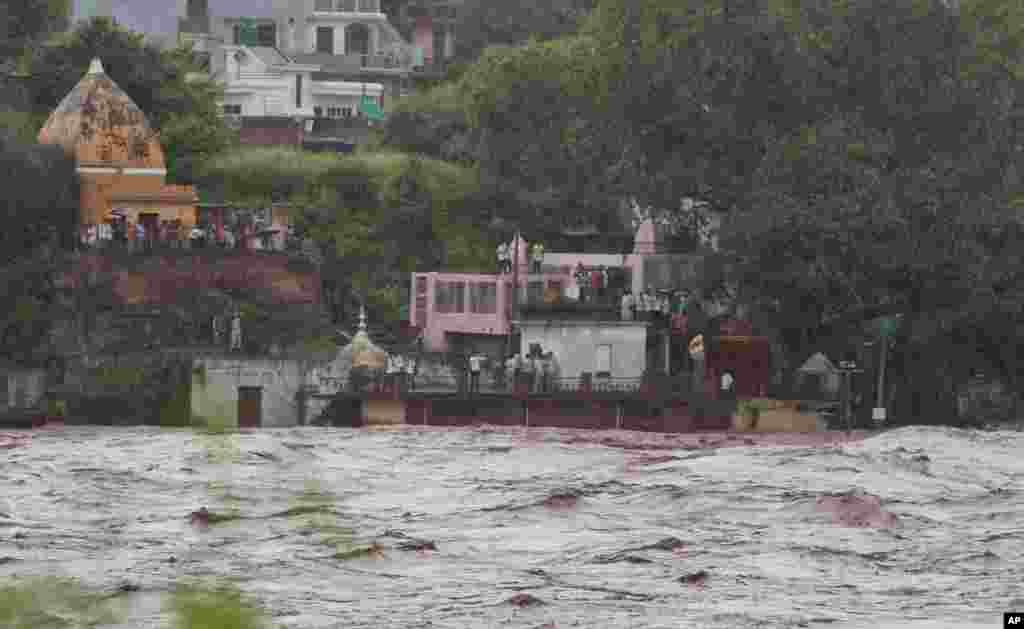 Residents watch the overflowing Chenab River after heavy rains, at Akhnoor, about 30 kilometers (19 miles) northwest of Jammu, India, Sept. 5, 2014.