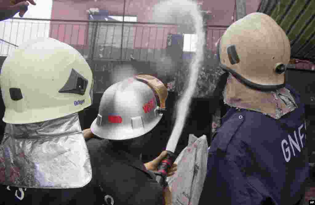 Bombeiros pulverizam água sobre uma estrutura remanescente de um posto de gasolina depois que explodiu em Acra, Gana, Quinta-feira, 4 de Junho, 2015. 