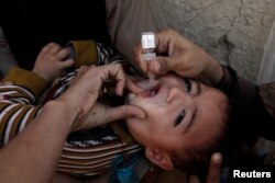 A boy receives polio vaccine drops by anti-polio vaccination workers along a street in Quetta, Pakistan, Jan. 2, 2017.