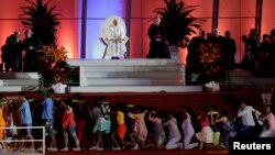 Paus Fransiskus (duduk di panggung) menyaksikan pertunjukan drama komedi yang digelar dalam perayaan Hari Pemuda Dunia di pantai Copacabana di Rio de Janeiro, di hari keempat kunjungan selama seminggunya di Brazil (25/7).