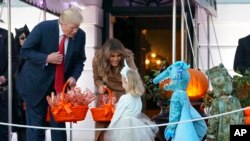 川普总统和第一夫人梅拉尼亚·川普在白宫南草坪给来自首都华盛顿地区的身穿各种万圣夜服装的孩子们分发糖果(2017年10月31日)