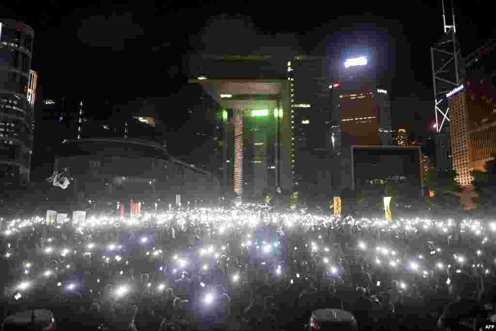 Protesters wave their mobile phones and other electronic devices as they take part in a pro-democracy rally next to the Hong Kong government complex. China announced rules giving it control over who can stand in Hong Kong&#39;s next leadership election, triggering tears and fury in the city where democracy activists vowed to stage a mass sit-in.