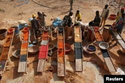 Artisanal miners sluice for gold by pouring water through gravel at an unlicensed mine near the city of Doropo, Ivory Coast, Feb. 13, 2018.
