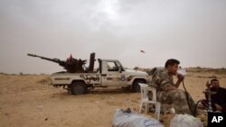 FILE - Libyan soldiers take a break from fighting with militants on the frontline in Al Ajaylat, 120 kilometers (75 miles) west of Tripoli, in this Feb. 21, 2015 photo.