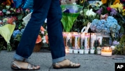 FILE - A woman walks past prayer candles left in front of the Emanuel AME Church in Charleston, South Carolina, several days after nine people were shot and killed during a Bible study, June 20, 2015.