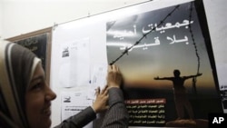 A female staff member of the Egyptian Organization For Human Rights hangs a poster that reads in Arabic "Unrestricted Non-Governmental Organizations" at their office in preparation for the November 28 parliamentary elections, in Cairo, 21 Nov 2010