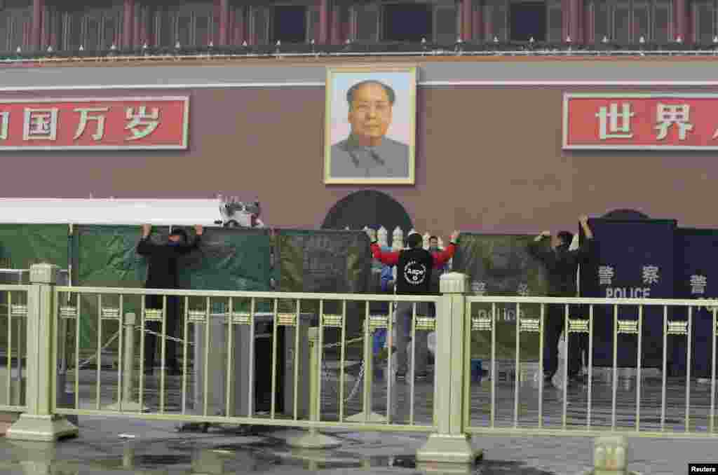 Police officers set up barriers in front of the giant portrait of the late Chinese Chairman Mao Zedong as they clean up after a car accident at Tiananmen Square in Beijing, Oct. 28, 2013. 