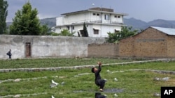 FILE - A boy plays with a tennis ball in front of Osama bin Laden's compound in Abbottabad, Pakistan, May 2011.